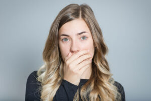 a dental implant patient with gum disease covering her mouth.