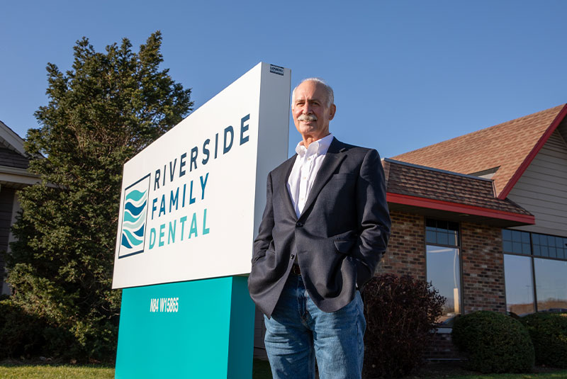 Patient smiling brightly after their dental treatment standing outside of the dental center