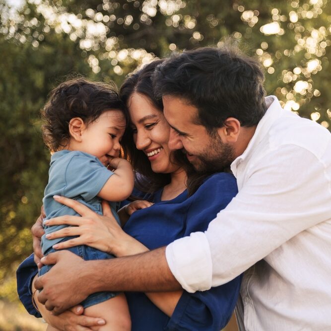 A joyful family embraces outdoors, embodying the warmth and care found at Riverside Family Dental